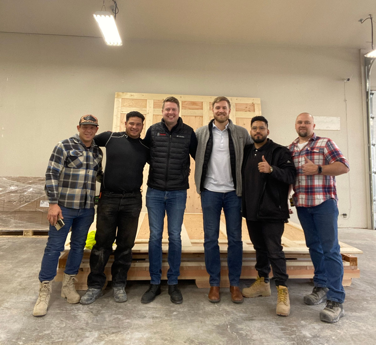 transpak-kalispell-team-posing-for-photo-in-front-of-wooden-crate