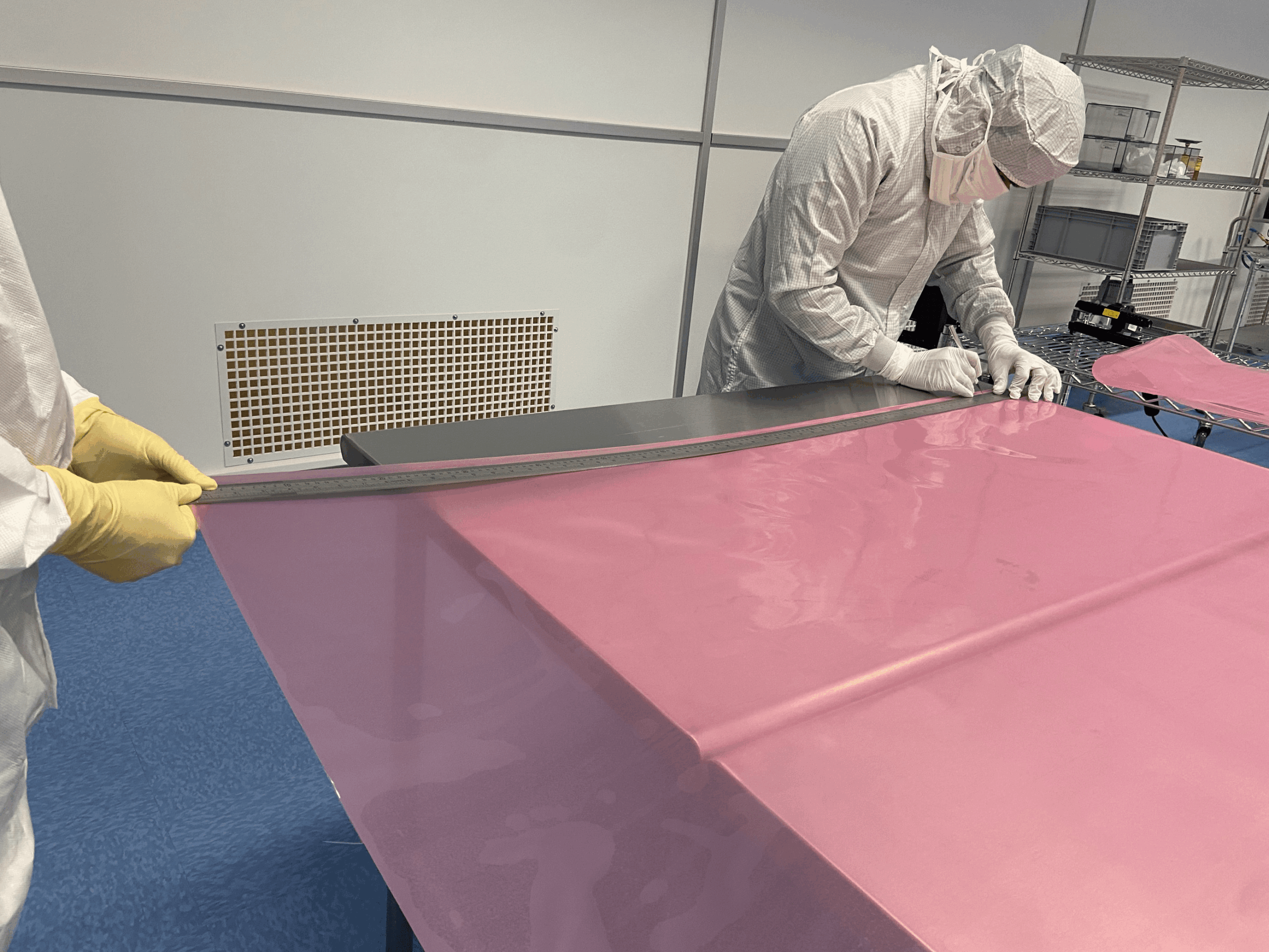 Two engineers measuring and marking a piece of plastic.